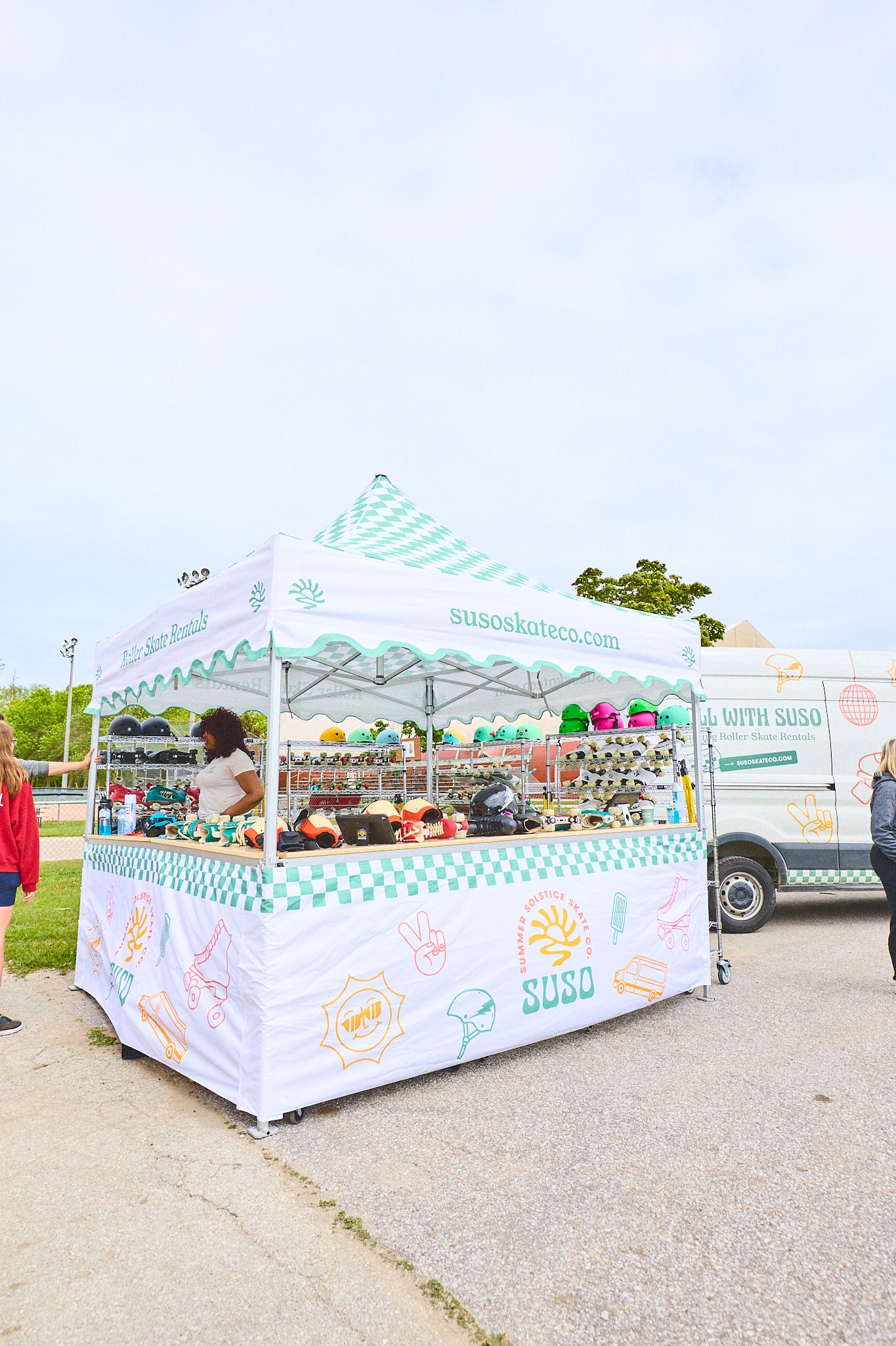 Roller skate van and tent with a white canopy and colorful branding on a clear day.